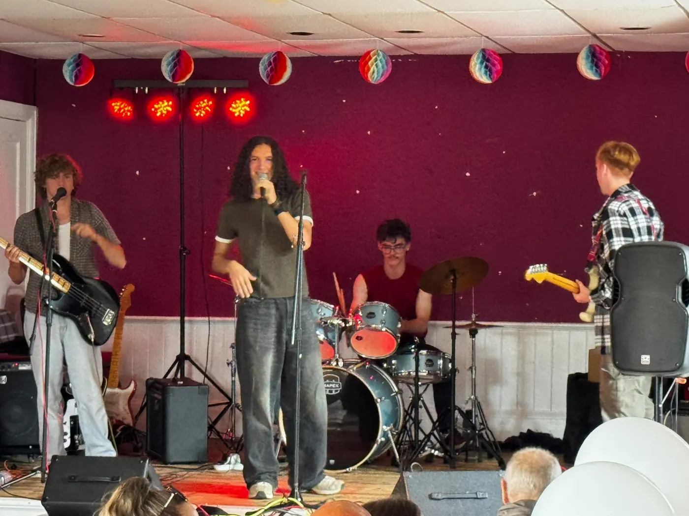 Full band under red stage lights at a village hall gig
