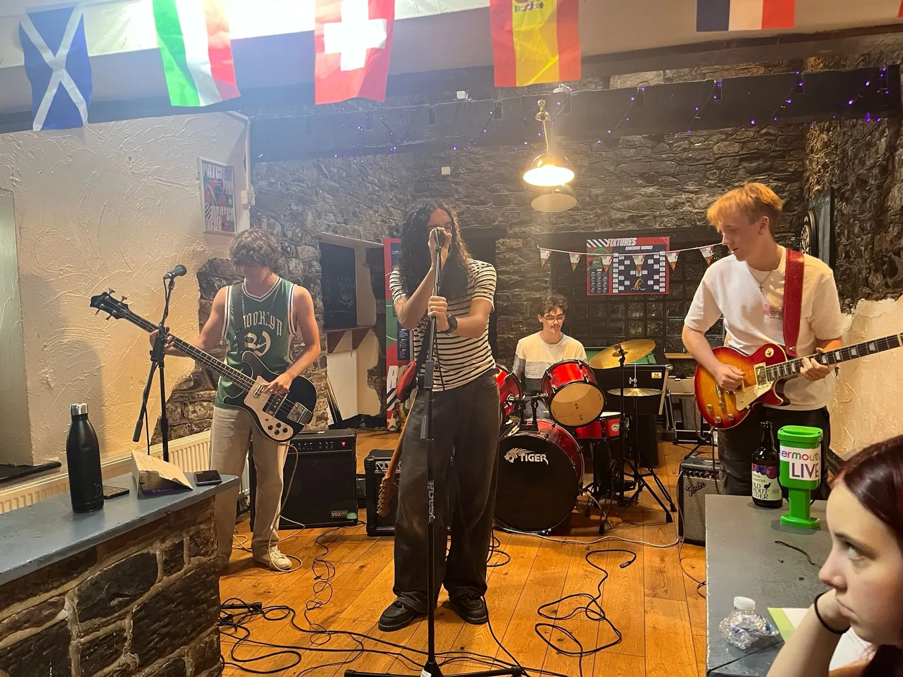 The Marratons mid set in a stone-walled pub, bass on the left, vocals centre, drums and lead guitar under the bunting